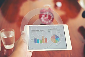 Business person hand holding financial statistics displayed on t