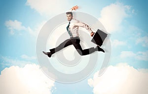 Business person jumping over clouds in the sky