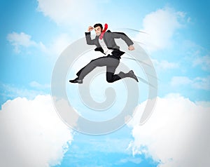 Business person jumping over clouds in the sky