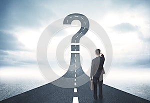 Business person lokking at road with question mark sign