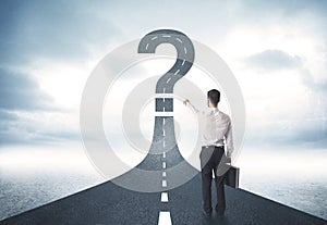 Business person lokking at road with question mark sign