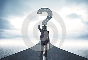 Business person lokking at road with question mark sign