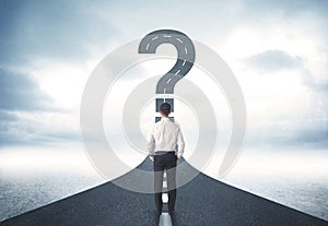 Business person lokking at road with question mark sign