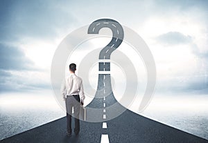 Business person lokking at road with question mark sign