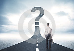 Business person lokking at road with question mark sign