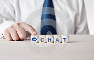 Business person pressing his finger on the wooden cubes with the word chat. Business client or customer online live chat support