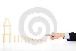 Business person pushing dominoes to destroy house photo