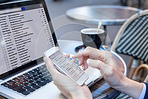 Business person reading emails on smartphone and laptop computer screen