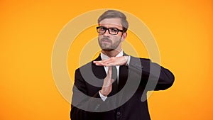 Business person showing time-out gesture, isolated on orange background deadline