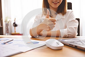 Business person working in office giving thumbs up for success