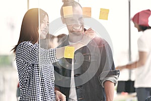 Business persons discussing work on a glass board