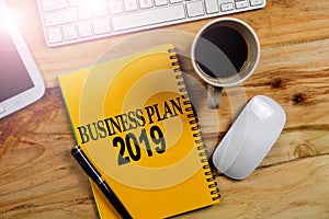 BUSINESS PLAN 2019 CONCEPT. Office desk table with laptop computer and coffee cup . Top view