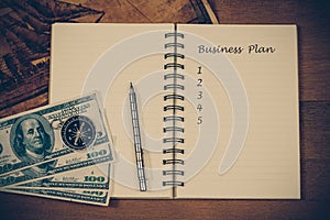 Business plan on book note with vintage compass and fountain pen over table