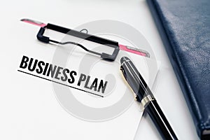 Business plan concept, pen and clipboard with word Business plan, glasses and diary book on white background with copy space