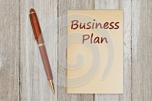 Business plan message on old paper notepad with a pen