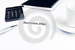 Business plan words near calculator, pen and cup of coffee, business concept