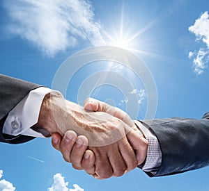 Business or political partnership concept. Close-up handshake against a blue sunny sky. Peace concept