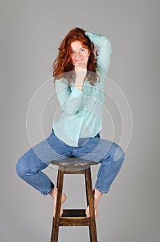 Business portrait of beautiful young woman with red curly hair and blue eyes against colorful background.