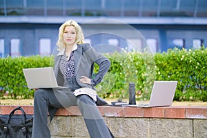 Business portrait of a woman. Businesswoman with two laptops working on the street