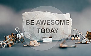 Business and positive concept. On torn paper the text is written - BE AWESOME TODAY