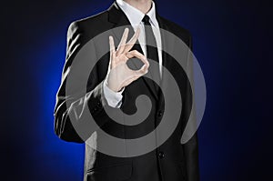 Business and the presentation of the theme: man in a black suit showing hand gestures on a dark blue background in studio isolated