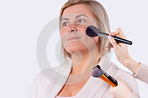 Business pretty blond woman with light complexion gets makeup for preparing for business meeting.