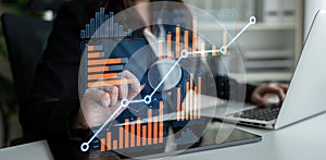 Business professional analyzing financial data using digital graphs on laptop in modern office environment with blurred