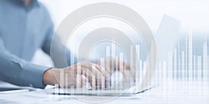 Business professional working on laptop with hands on keyboard, surrounded by data visualizations and graphs