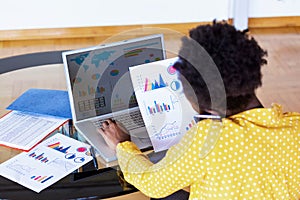 Business professionals. Business woman analyzing data using computer while spending time in the office. Beautiful young grinning