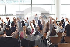 Business professionals raising hands in a business seminar