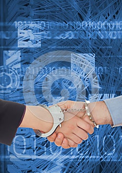 Business professionals shaking hands in handcuffs against coding background