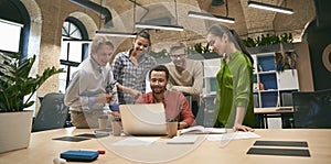 Business professionals at work. Multicultural team, group of young cheerful business people analyzing data, looking at