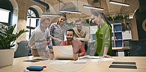 Business professionals at work. Multicultural team, group of young cheerful business people analyzing data, looking at photo