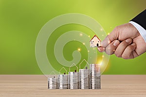 Business property investment with business man hand stacking coin growing growth with house model on wooden desk with green