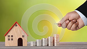 Business property investment with businessman hand stacking coin growing growth with house model on wooden desk with green