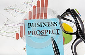 BUSINESS PROSPECT - a word on a piece of paper for notes on the background of a graph and glasses