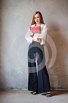 Business redhead woman in white shirt and black pants with folders of documents.
