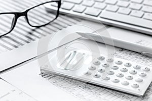 Business report preparing with calculator and glasses on office background