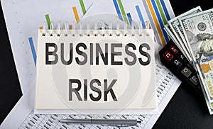 BUSINESS RISK text written on notebook with chart,calculator and dollars