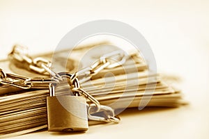 Business safety or financial protection or restriction access. Heap of money in chain with padlock isolated on white