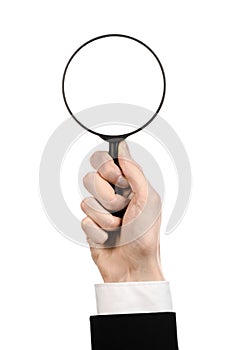 Business Search topic: businessman in a black suit holding a magnifying glass on a white isolated background