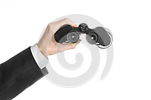 Business and search topic: Man in black suit holding a black binoculars in hand on white isolated background in studio