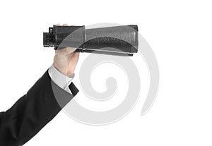 Business and search topic: Man in black suit holding a black binoculars in hand on white isolated background in studio