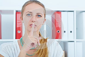 Business secret concept. Young business woman making hush sign.