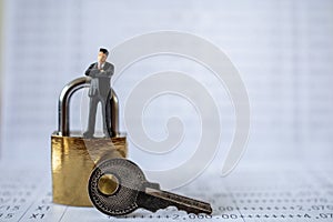 Business and Security Concept. Businessman miniature figure people standing on gold master key lock with silver key on bank