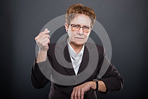 Business senior lady showing time is money gesture