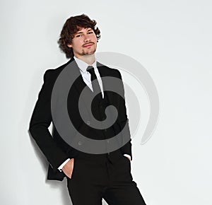 Business sexy man in black fashion suit posing on gray wall bacground with smiling happy face. Closeup studio