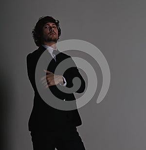 Business sexy man in black fashion suit posing on gray wall background with serious face and passion angry look. Closeup studio