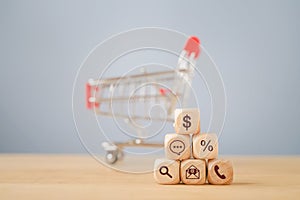 Business shopping icon on wooden cube and blurred shopping cart on wood