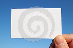 Business sized white card close up in the blue sky